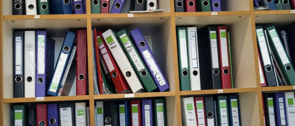 Regal mit dicht gestellten Aktenordnern in einem Büro.